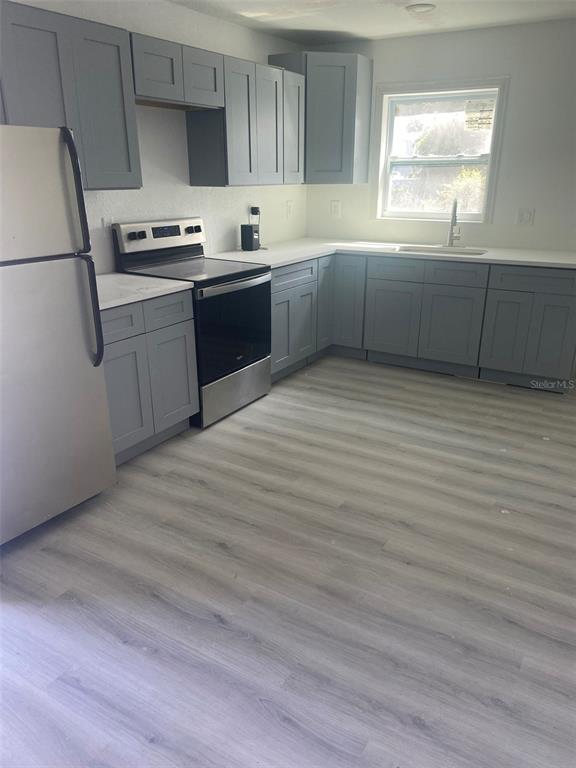 A kitchen features gray cabinets, stainless steel appliances, white countertops, and light wood-look flooring — 3490 13TH AVENUE S, ST PETERSBURG, FL