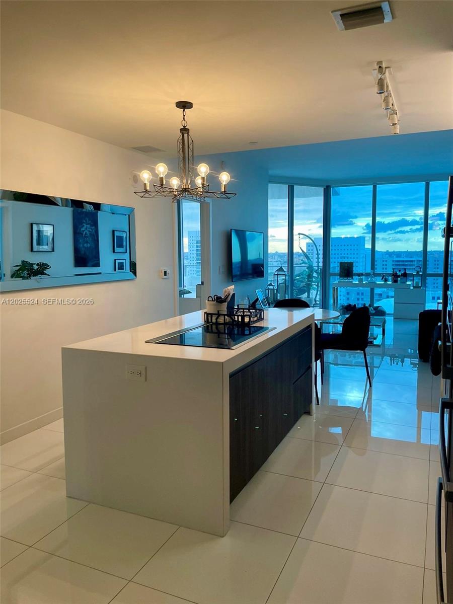 A modern kitchen features a large white island with a cooktop and dark cabinetry — 851 NE 1st Ave # 1808, Miami FL 33132, MIAMI, FL