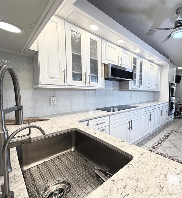 A galley kitchen features white cabinets, stainless steel appliances, and light-colored granite countertops — 5813 MERION WAY UNIT 5813, SARASOTA, FL