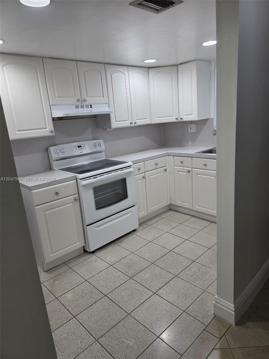 A kitchen features white cabinets, a white stove, and light-colored tile flooring — 40 NW 87th Ave # D201, Miami FL 33172, MIAMI, FL