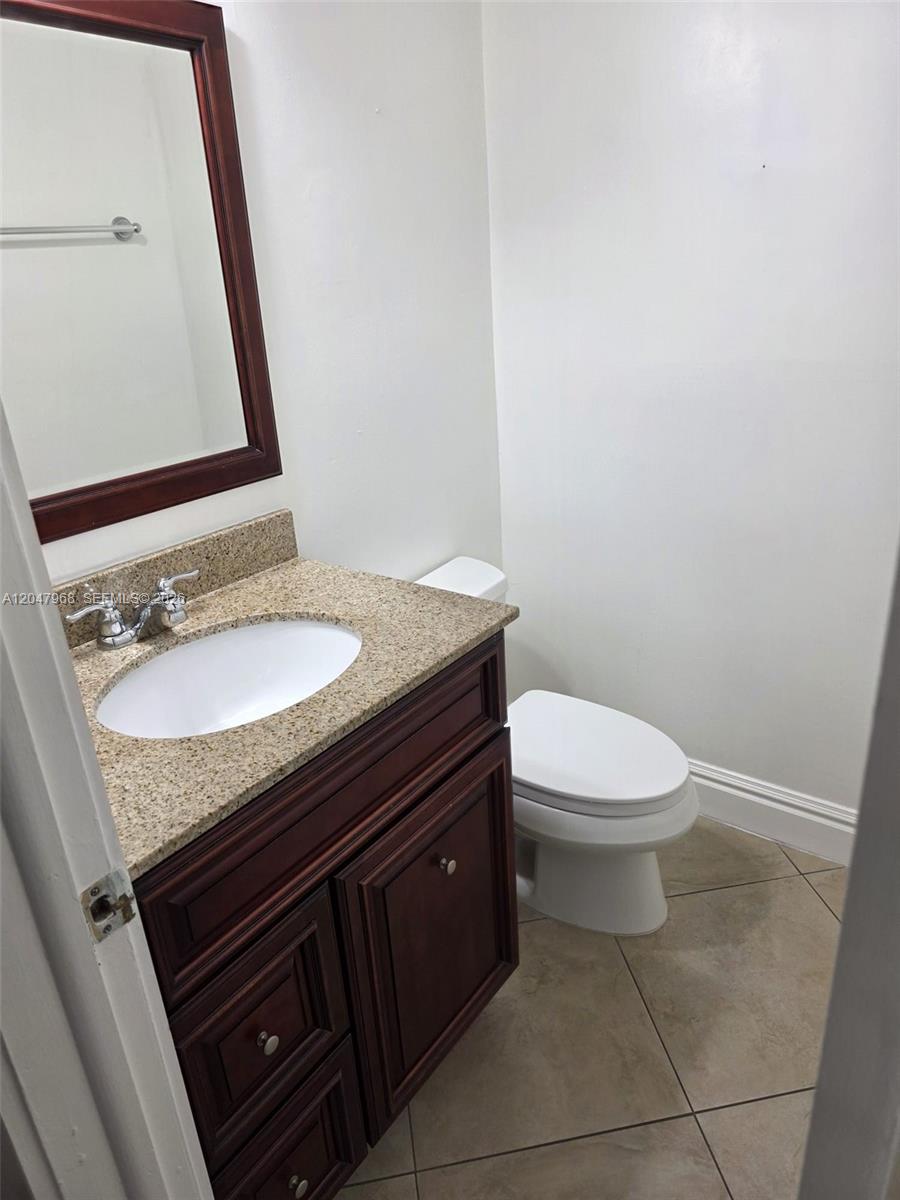 A bathroom features a granite vanity, dark wood cabinetry, a mirror, and a white toilet — 40 NW 87th Ave # D201, Miami FL 33172, MIAMI, FL