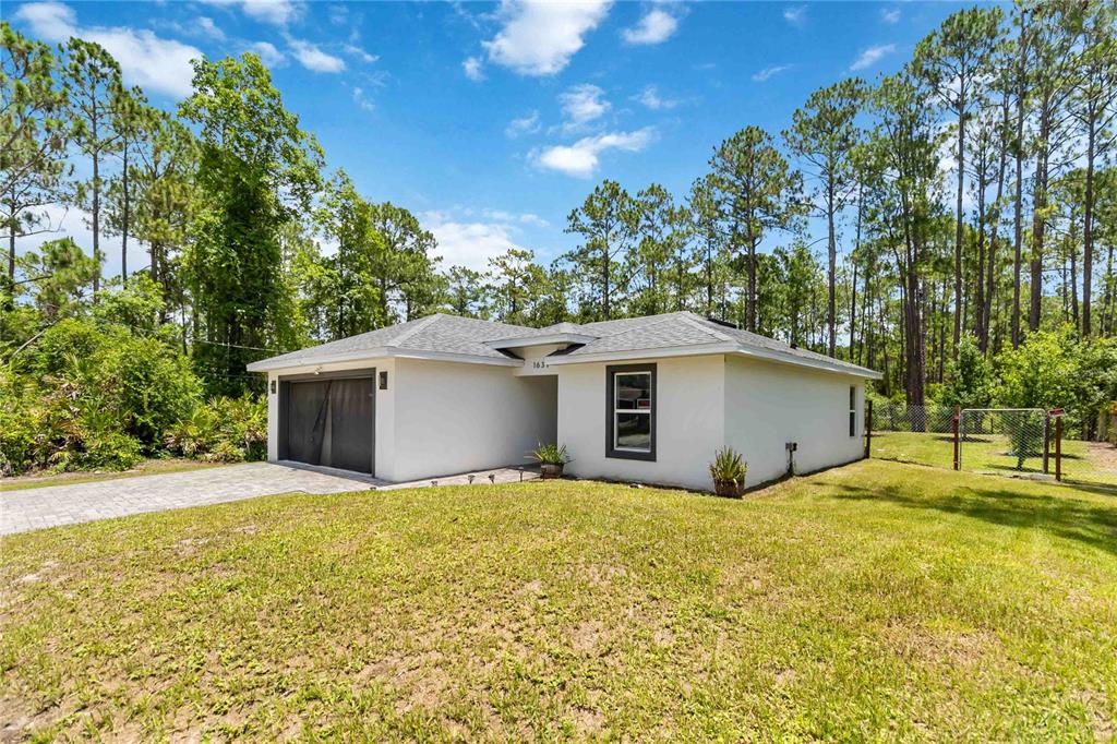 A single-story house with a white exterior, a garage, and a large grassy yard — 1639 11TH AVENUE, DELAND, FL