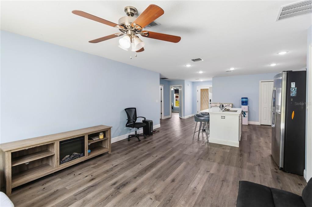 A living room with light blue walls, wood-look flooring, a ceiling fan, and a kitchen island — 1639 11TH AVENUE, DELAND, FL