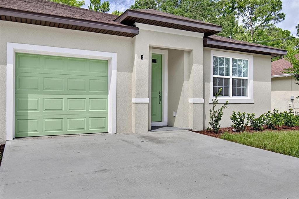 A single-story house exterior features a green garage door, a green front door, and a driveway — 14 ULLYNN PLACE UNIT B, PALM COAST, FL