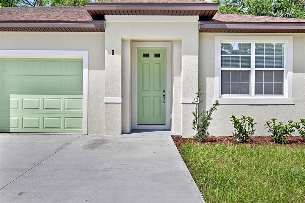 The exterior of a house features a light green garage door and matching front door — 14 ULLYNN PLACE UNIT B, PALM COAST, FL