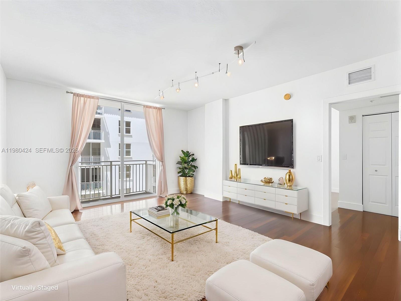 A bright living room features white furniture, a glass coffee table, and a balcony view — 2030 S Douglas Rd # 610, Coral Gables FL 33134, CORAL GABLES, FL