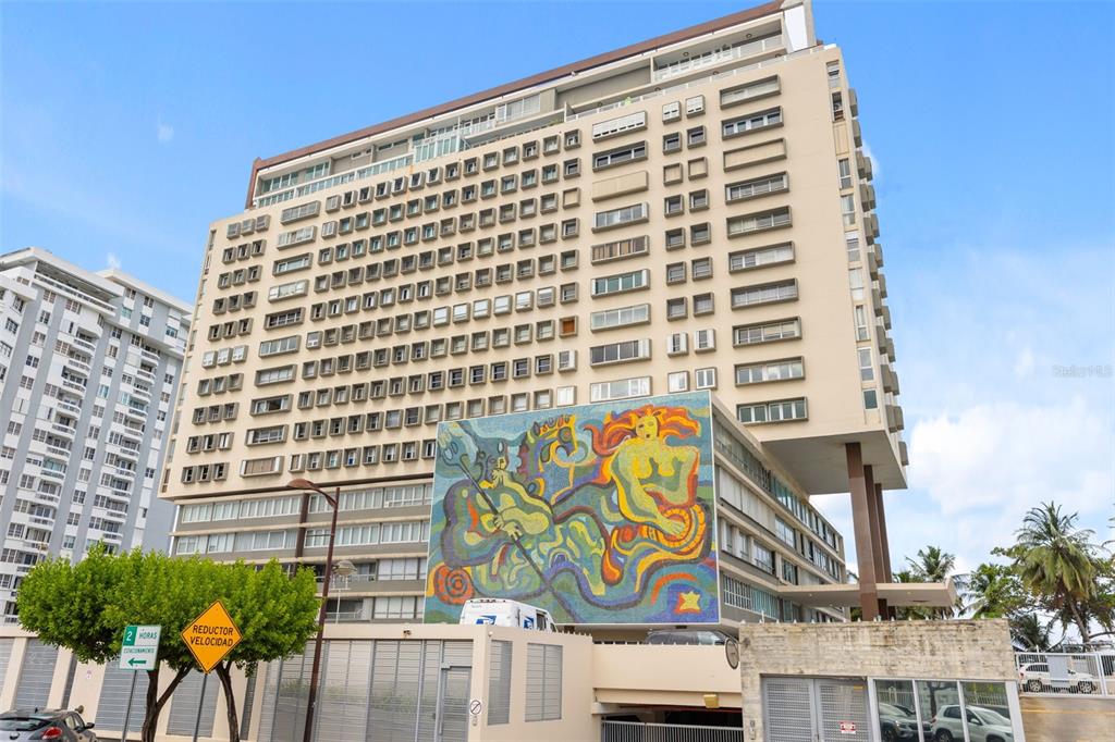 A tall, multi-story apartment building features a large, colorful mosaic mural on its exterior wall — 3307 AVE ISLA VERDE UNIT PH, CAROLINA, PR