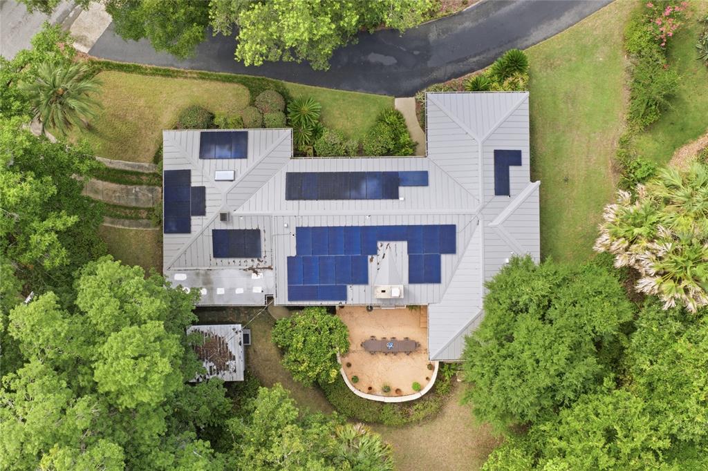 An aerial view shows a house with a metal roof and several solar panel arrays — 2006 NW 14TH AVENUE, GAINESVILLE, FL