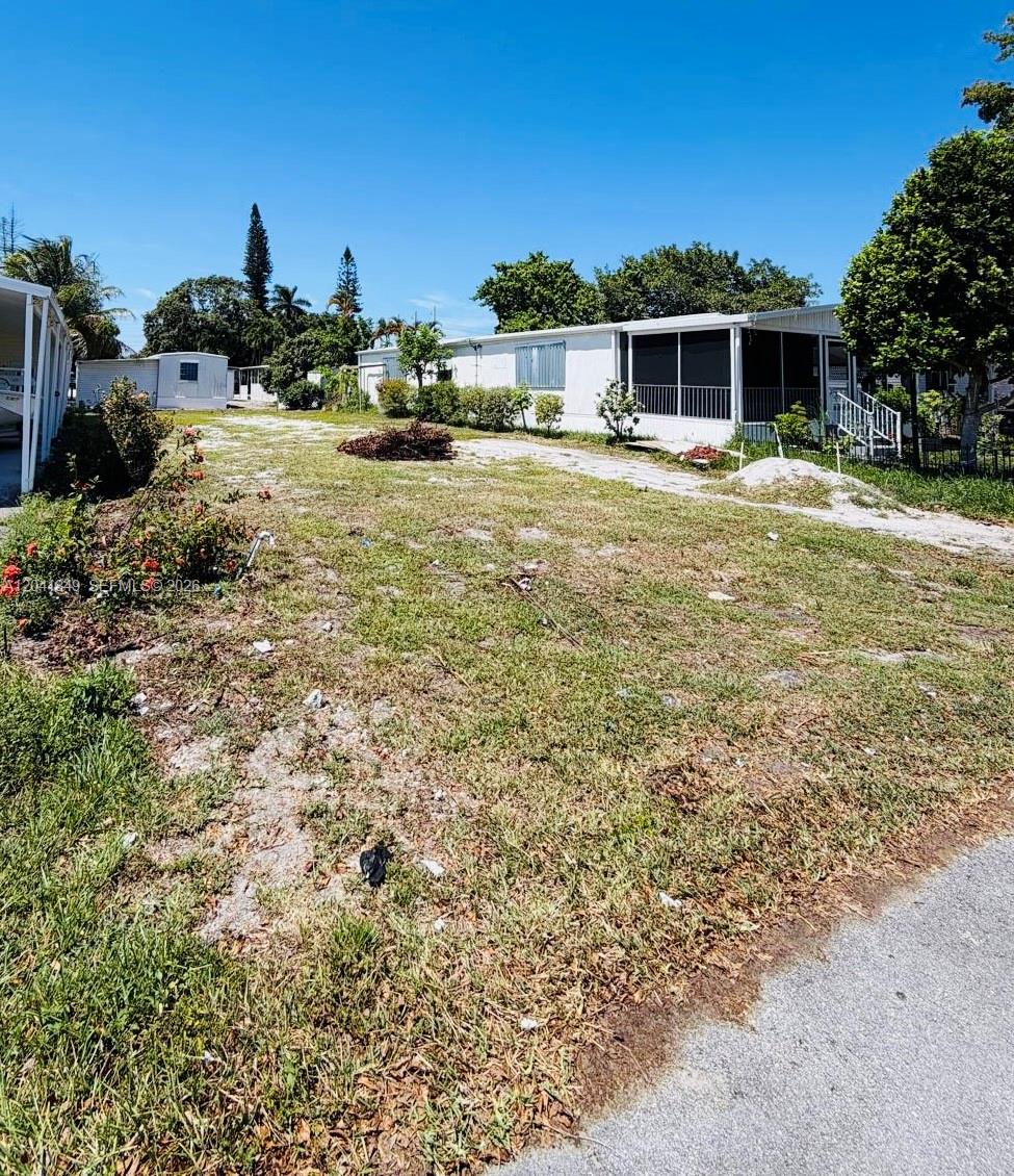 A grassy lot sits in front of a white mobile home with a screened porch — 2651 E Marina Dr, Dania Beach FL 33312, DANIA BEACH, FL
