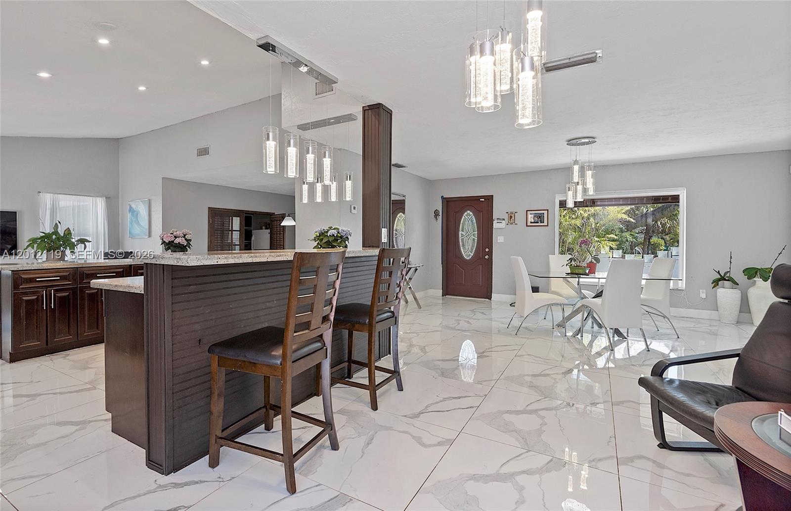 A kitchen with a breakfast bar and dining area features white marble-look tile flooring — 8895 SW 184th Ter, Cutler Bay FL 33157, CUTLER BAY, FL