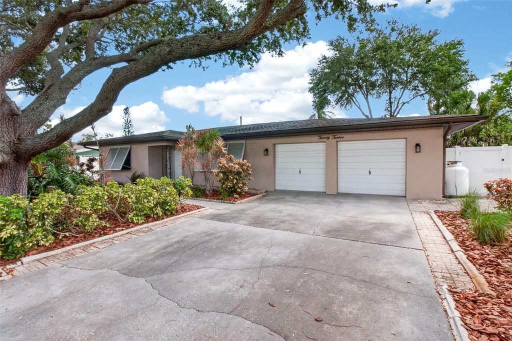 A single-story house with a two-car garage, a concrete driveway, and a large oak tree — 2012 RIPON DRIVE, CLEARWATER, FL