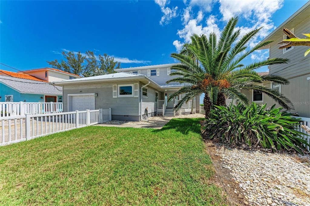 A two-story gray house with a white fence, a palm tree, and a grassy yard — 893 N SHORE DRIVE, ANNA MARIA, FL