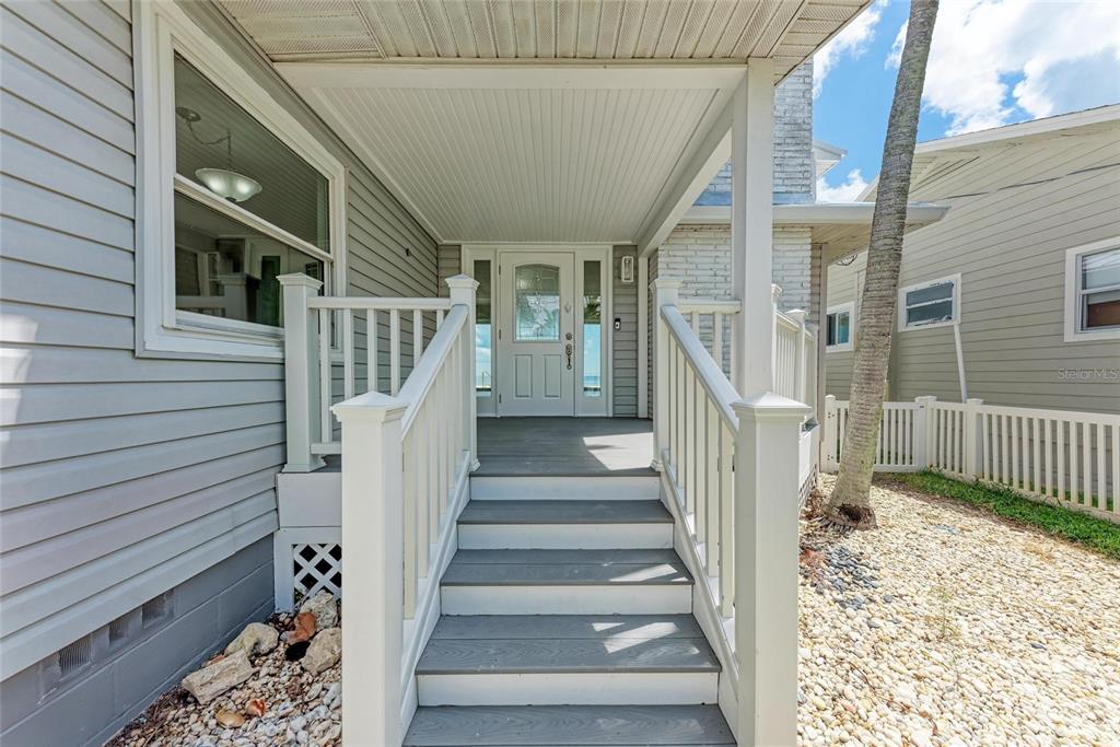 A front porch with wooden steps leads to a white door under a covered entryway — 893 N SHORE DRIVE, ANNA MARIA, FL