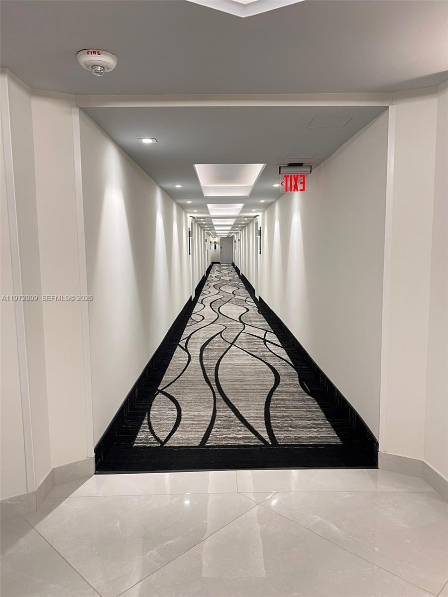 A long hotel hallway features white walls, recessed ceiling lighting, and a patterned carpet runner — 3180 S Ocean Dr # 1418, Hallandale Beach FL 33009, HALLANDALE BEACH, FL
