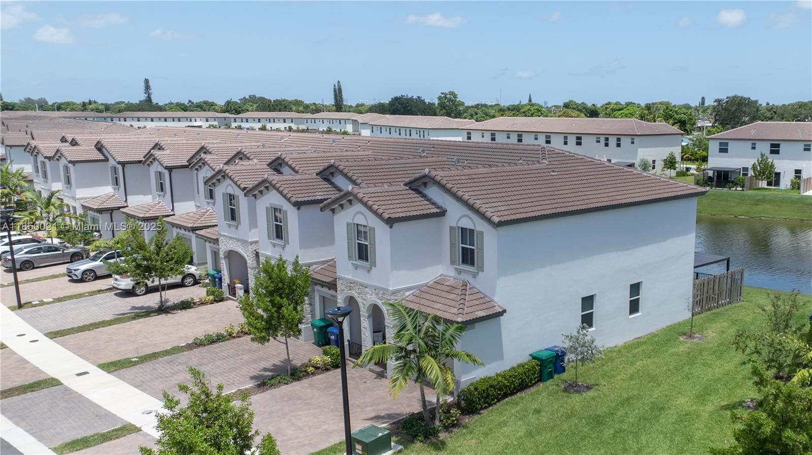 An aerial view shows a row of two-story townhouses with tiled roofs and driveways — 12561 NW 23rd Pl, Miami FL 33167, MIAMI, FL