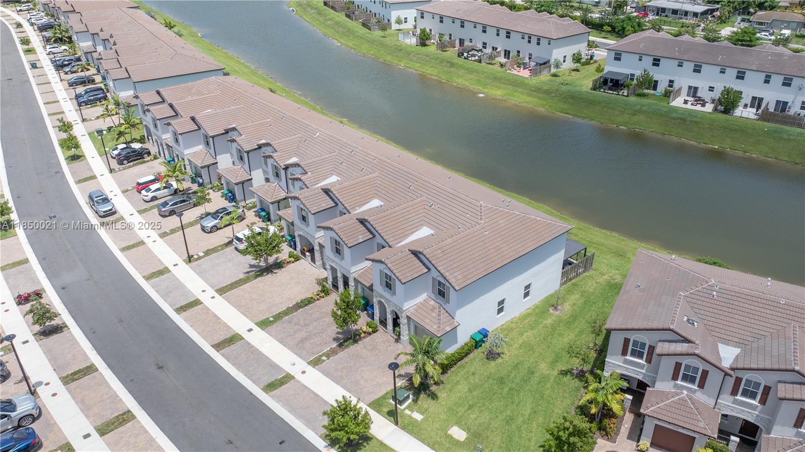 An aerial view shows a row of townhouses with brown tile roofs beside a canal — 12561 NW 23rd Pl, Miami FL 33167, MIAMI, FL
