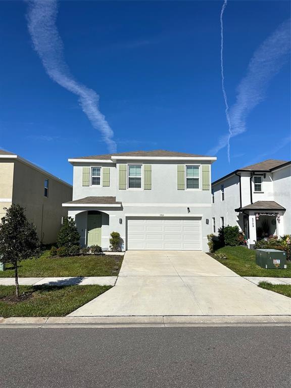 A two-story suburban house with a light-colored stucco exterior and a two-car garage — 5703 HOLLINGWORTH TRAIL, WESLEY CHAPEL, FL