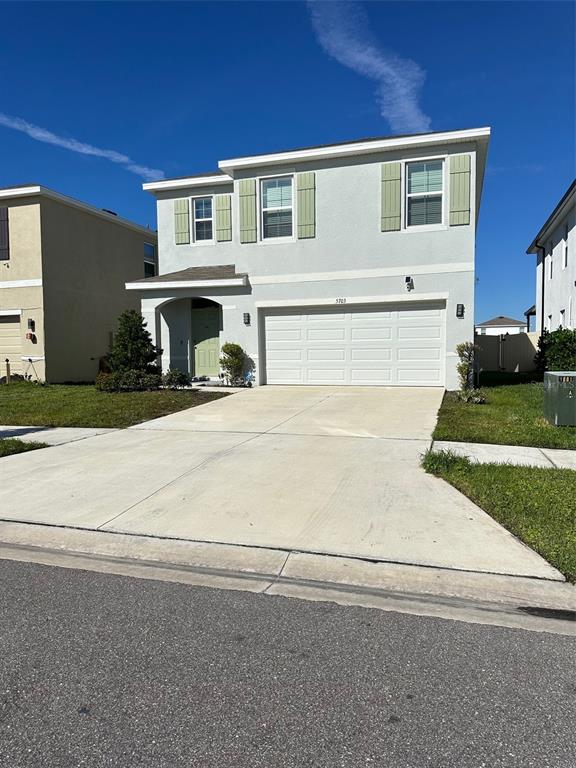A two-story house with a light gray exterior, a two-car garage, and green shutters — 5703 HOLLINGWORTH TRAIL, WESLEY CHAPEL, FL