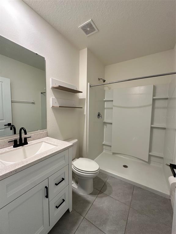 A bathroom features a white vanity, a toilet, and a walk-in shower with white walls — 5703 HOLLINGWORTH TRAIL, WESLEY CHAPEL, FL