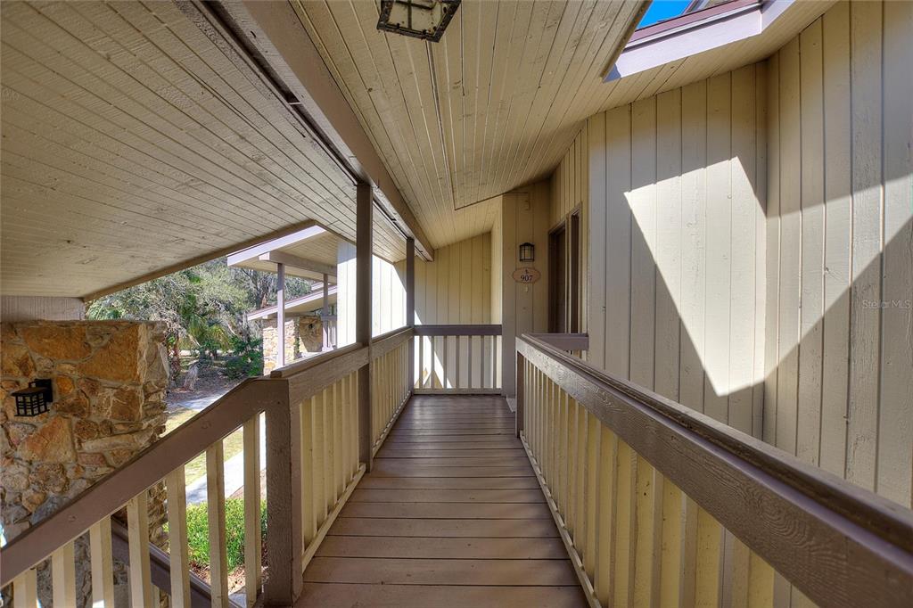 An elevated wooden walkway leads to a building entrance with light-colored vertical siding — 907 TENNIS WAY UNIT 3147/8, HAINES CITY, FL