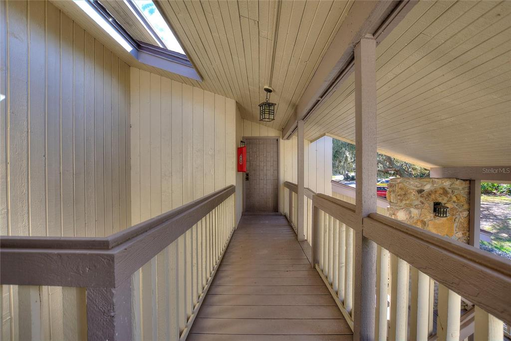 A wooden walkway with railings leads to a door under a covered outdoor porch — 907 TENNIS WAY UNIT 3147/8, HAINES CITY, FL