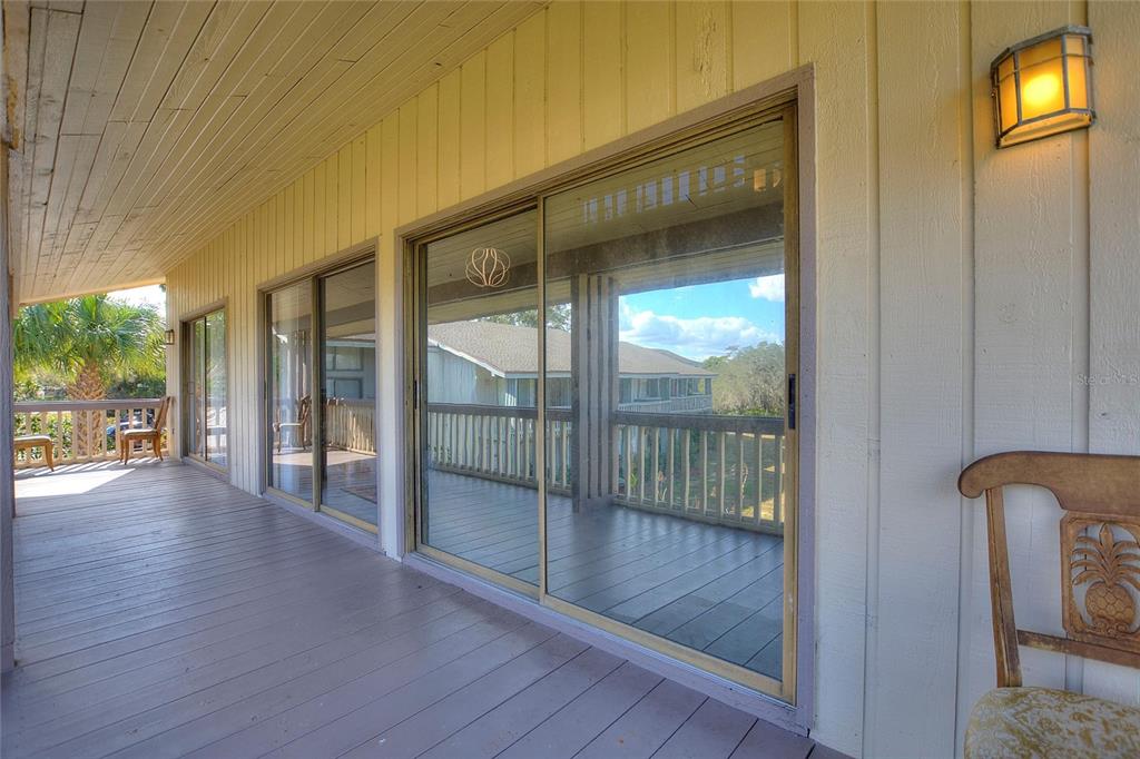 A covered wooden deck features sliding glass doors and a wall-mounted light fixture — 907 TENNIS WAY UNIT 3147/8, HAINES CITY, FL