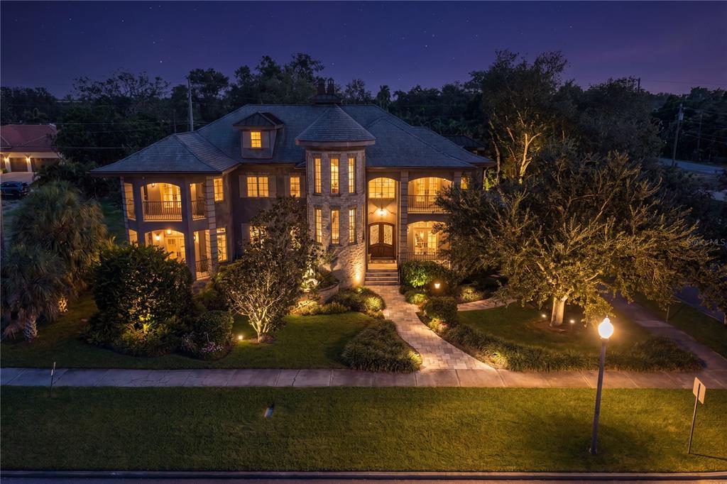 An aerial view of a multi-story stone and stucco house at night with illuminated windows — 401 SNELL ISLE BOULEVARD NE, ST PETERSBURG, FL
