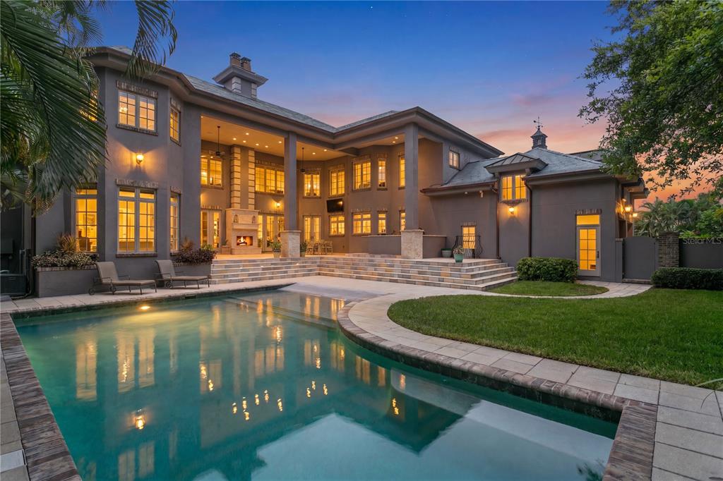 A large two-story house with a swimming pool and a multi-level stone patio at dusk — 401 SNELL ISLE BOULEVARD NE, ST PETERSBURG, FL