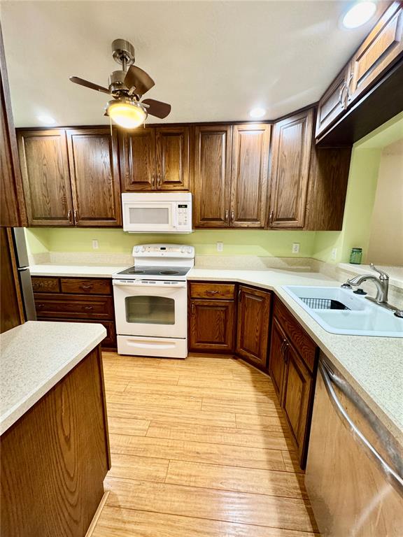 A kitchen features wood cabinets, white appliances, light countertops, and light wood-look flooring — 7 MOSER COURT N, HOMOSASSA, FL