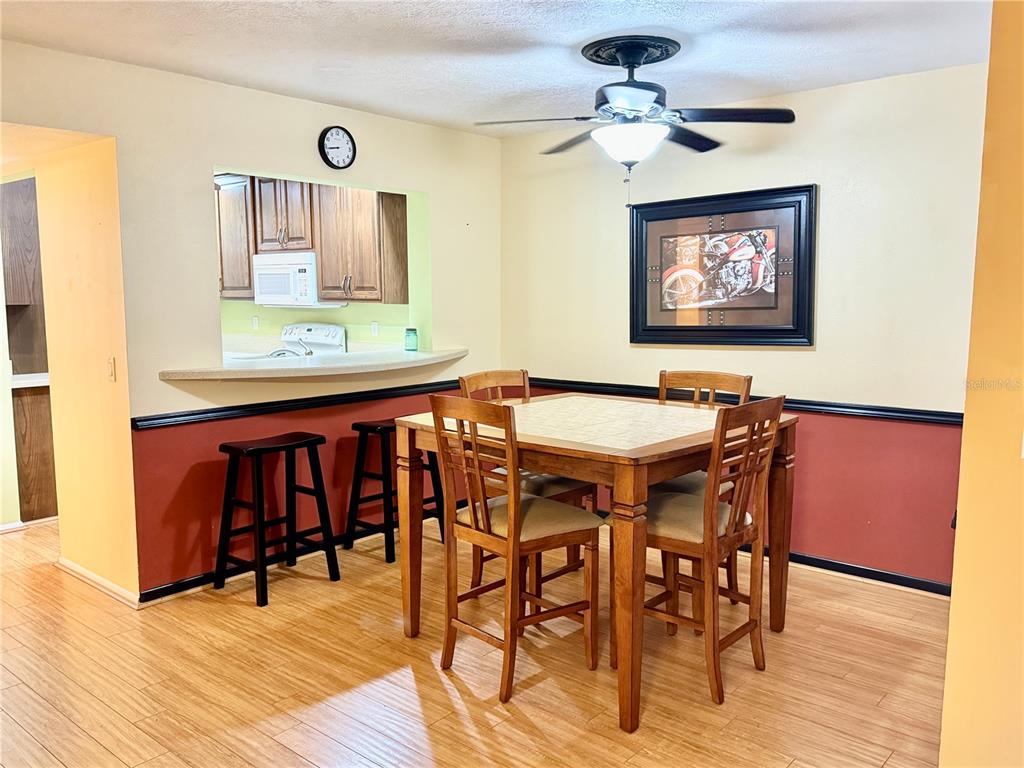 A dining area features a wooden table with four chairs, bar stools, and a ceiling fan — 7 MOSER COURT N, HOMOSASSA, FL