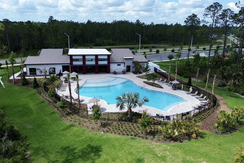 An aerial view shows a community clubhouse with a large swimming pool and patio area — 1291 RIBBON PLACE, PALM COAST, FL
