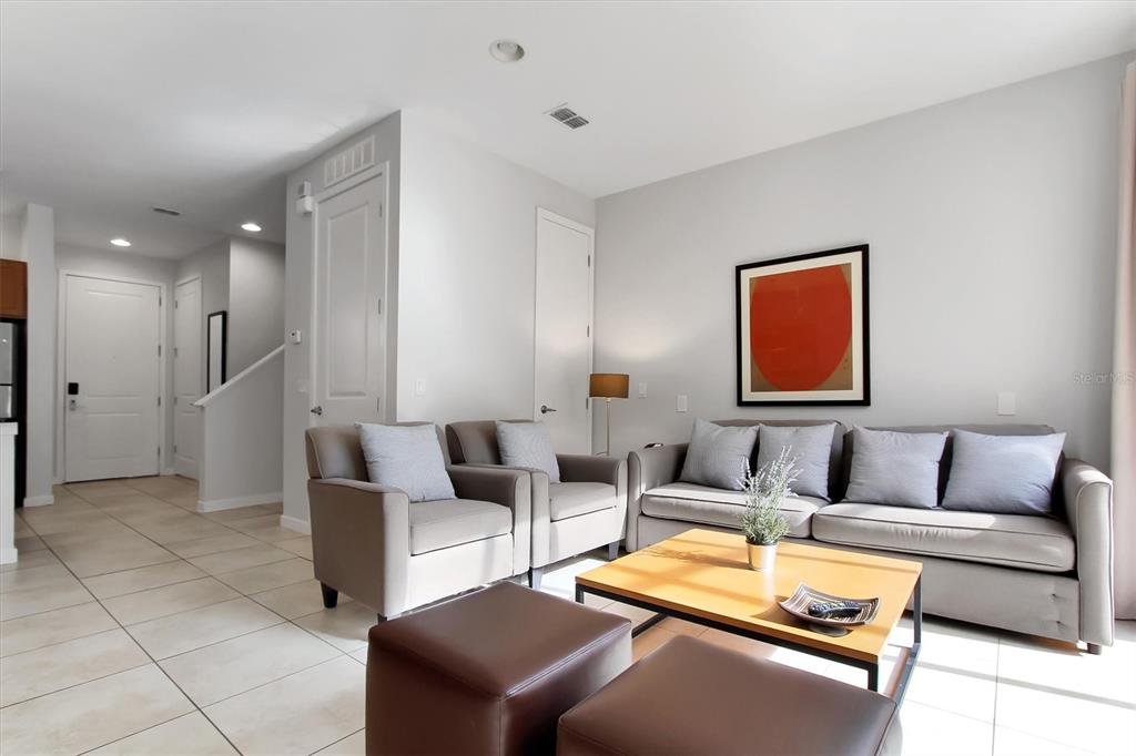 A living room features gray furniture, a wooden coffee table, and tile flooring — 2691 CORVETTE LANE, KISSIMMEE, FL