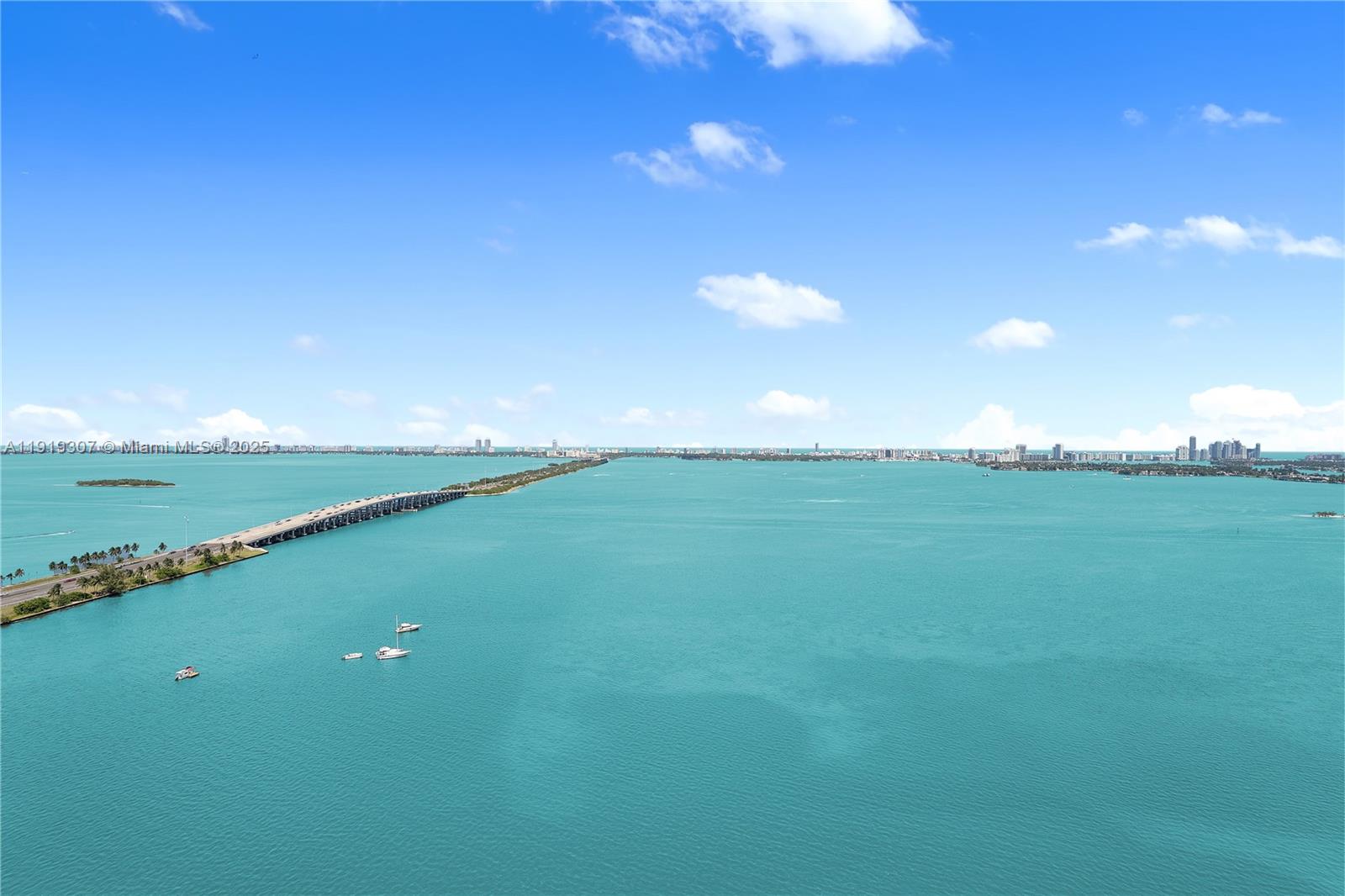 An aerial view shows a long bridge spanning across a large, turquoise bay — 3131 NE 7th Ave # 3106, Miami FL 33137, MIAMI, FL