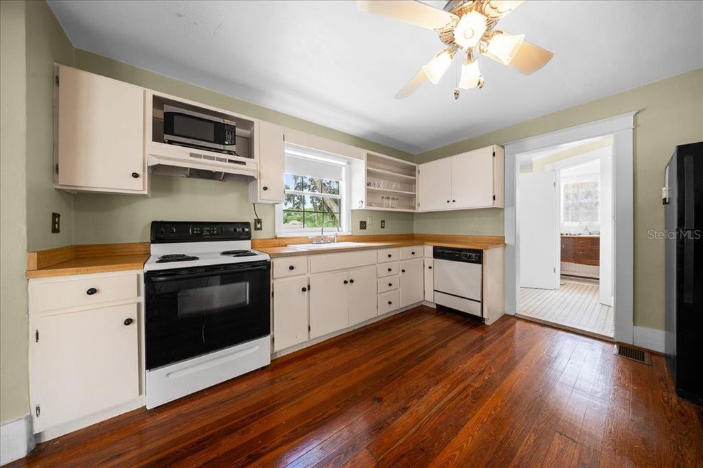 A kitchen with white cabinets, wood countertops, hardwood floors, and a ceiling fan — 319 CARNATION COURT, APOPKA, FL