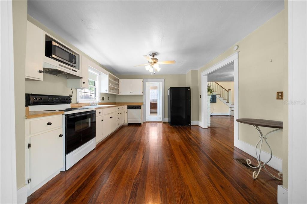 A kitchen with white cabinets, wood floors, and a black refrigerator — 319 CARNATION COURT, APOPKA, FL