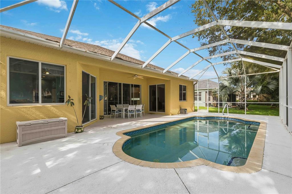 A backyard swimming pool with a screened enclosure sits next to a yellow house — 8268 47TH STREET CIRCLE E, PALMETTO, FL