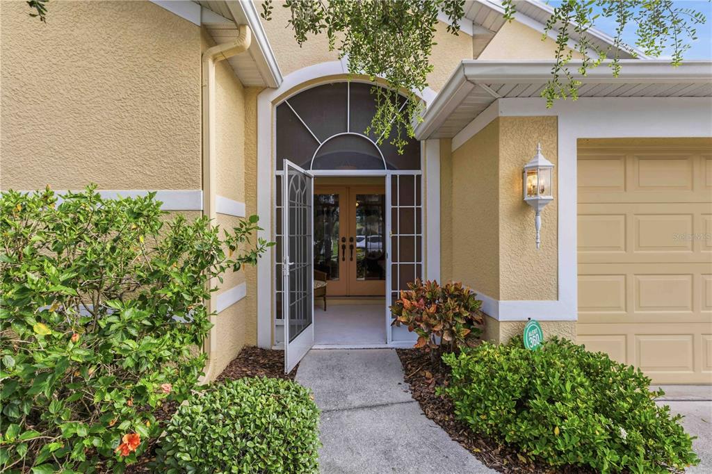 The exterior view shows a yellow house with a screened entryway and double front doors — 8268 47TH STREET CIRCLE E, PALMETTO, FL
