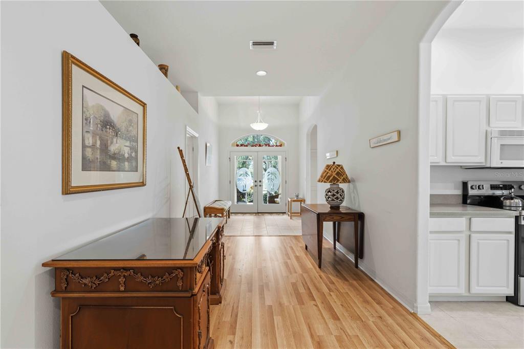 A foyer with wood flooring leads to a glass-paneled front door with a transom window — 8268 47TH STREET CIRCLE E, PALMETTO, FL