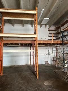 An industrial warehouse space features a multi-level metal racking system and a wooden mezzanine platform — 1750 W 39th Place # 1005, Hialeah FL 33012, HIALEAH, FL