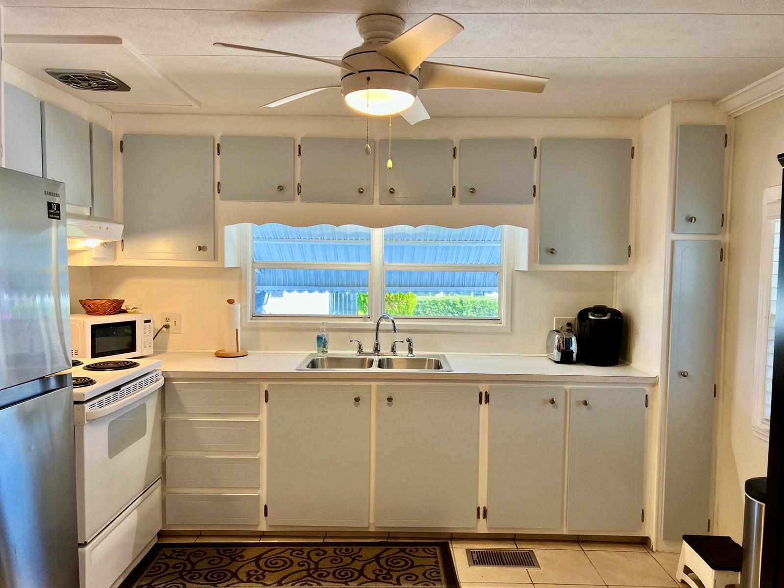 A kitchen features light blue cabinets, white countertops, a double sink, and a ceiling fan — 1552 S 33rd Road, Hollywood FL 33021, HOLLYWOOD, FL