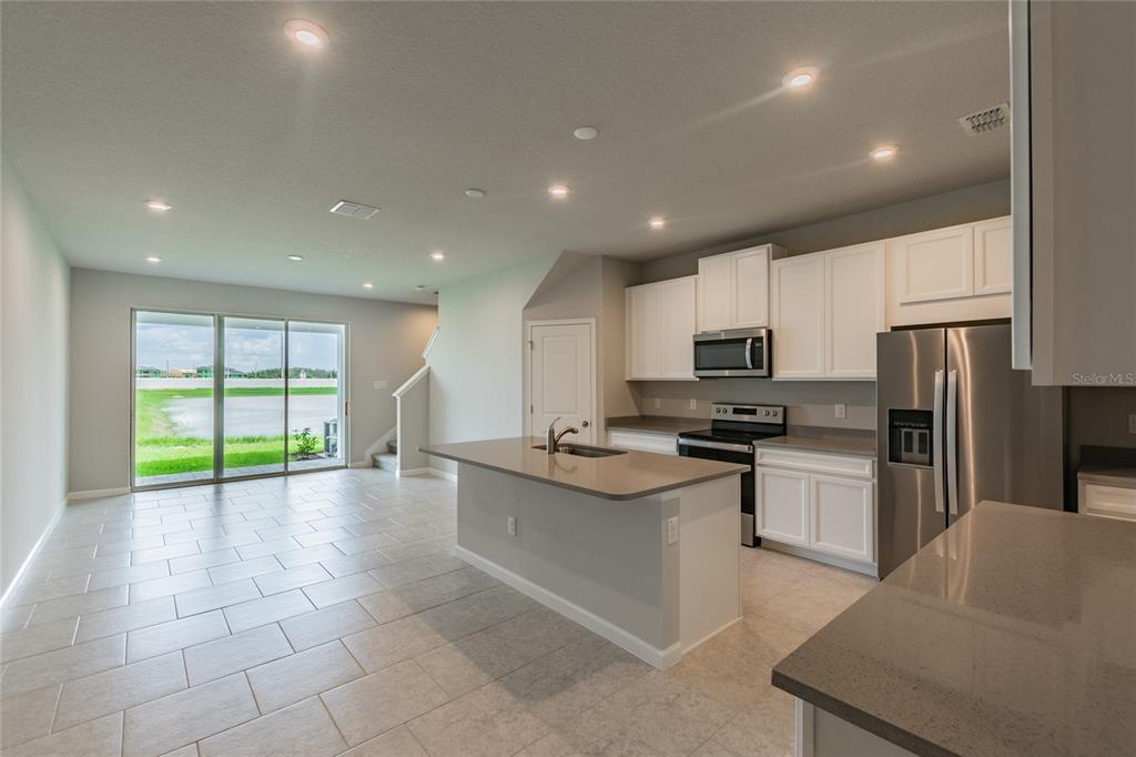 A kitchen with a central island, white cabinets, stainless steel appliances, and sliding glass doors — 19309 BLUE POND DRIVE, LUTZ, FL