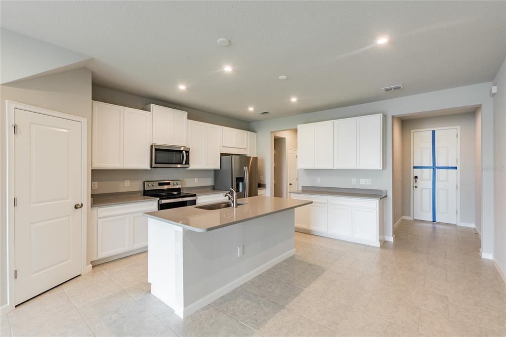 A kitchen with white cabinets, stainless steel appliances, a center island, and tile flooring — 19309 BLUE POND DRIVE, LUTZ, FL