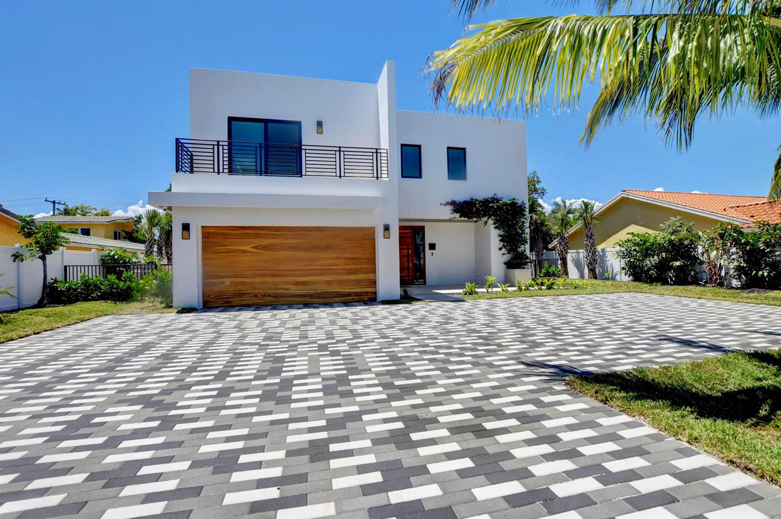A modern two-story white house features a wooden garage door and a patterned paver driveway — 855 NW 4th Avenue, Boca Raton FL 33432, BOCA RATON, FL