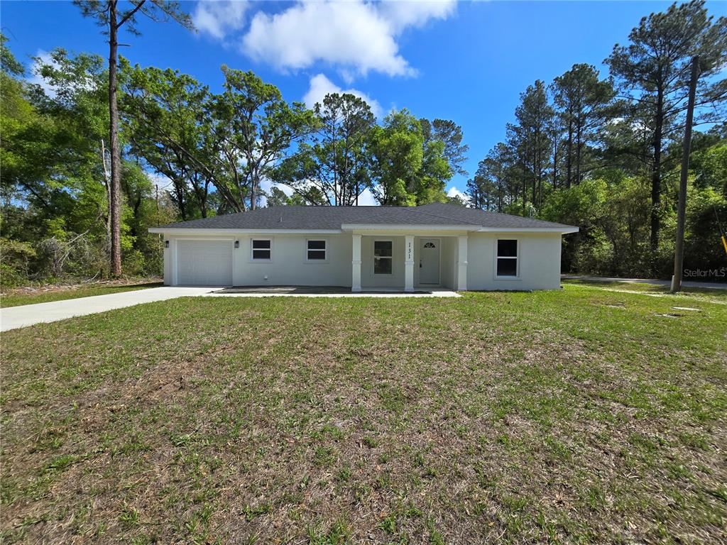 A single-story house with a white exterior, a front porch, and an attached garage — 131 FISHER ROAD, OCKLAWAHA, FL