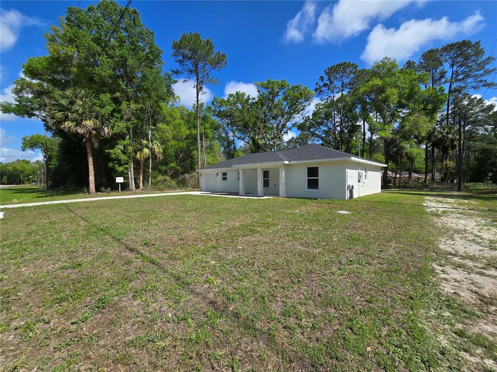 A single-story house with a light-colored exterior sits on a large, grassy lot — 131 FISHER ROAD, OCKLAWAHA, FL