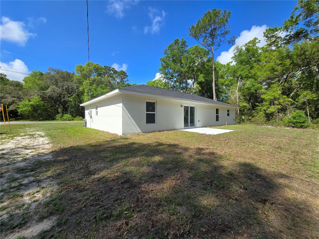 A white, single-story house with a small concrete patio sits on a grassy lot — 131 FISHER ROAD, OCKLAWAHA, FL