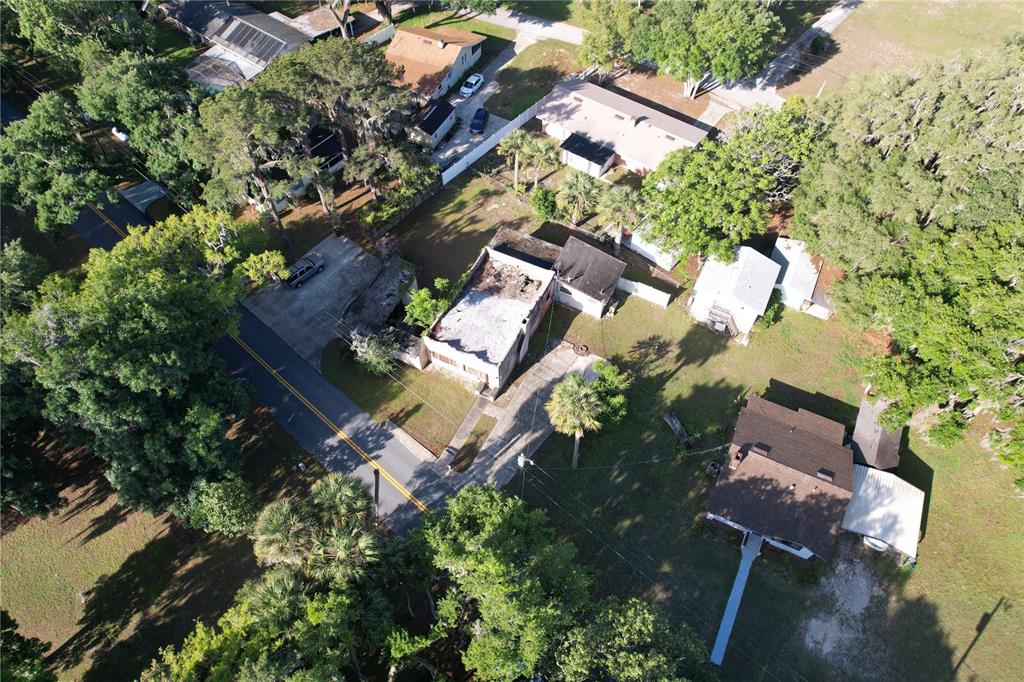 An aerial view shows a residential property with a damaged roof and surrounding trees — 6405 SUNNYSIDE DRIVE, LEESBURG, FL