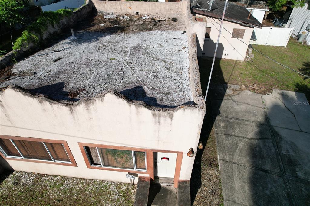 An aerial view shows a single-story building with a flat, weathered roof and stucco exterior — 6405 SUNNYSIDE DRIVE, LEESBURG, FL