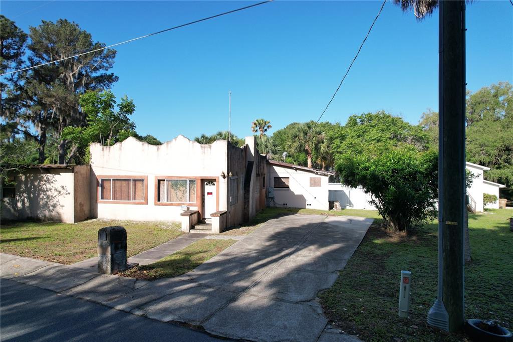 A single-story stucco house with a scalloped roofline and a concrete driveway — 6405 SUNNYSIDE DRIVE, LEESBURG, FL