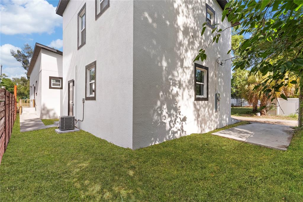 A side view of a white stucco house with dark trim and a grassy yard — 1421 35TH STREET S, ST PETERSBURG, FL